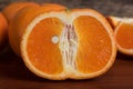 Half and whole fresh oranges on wooden table