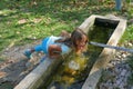 4 and a half year old girl drinks from a fountain in a forest