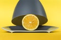 Half a yellow lemon under the hood on a gray plate on a yellow background Royalty Free Stock Photo