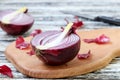 Halfs of red onion is located on a wooden board on a table