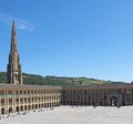 People relaxing and enjoying the summer sunshine in the square of halifax piece hall in west yorkshire with surrounding hills and