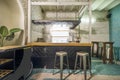 Hall of a restaurant with an industrial style bar counter made of wood and metal, green floors, brick arches, and high wooden