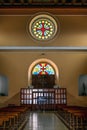 Hall with wooden benches and a round stained-glass window above the entrance Royalty Free Stock Photo