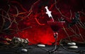 Halloween alcoholic cocktail bloody martini with syringe on scary dark red background with twisted branches, bats, stones, pumpkin Royalty Free Stock Photo