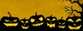 HALLOWEEN background banner template -Silhouette of scary carved luminous cartoon pumpkins and trees isolated in dark yellow night Royalty Free Stock Photo