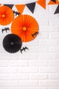 Halloween background. Black and orange paper decorations for Halloween on a white brick wall. Party flags, bats, paper fans. Copy Royalty Free Stock Photo