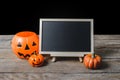 The chalkboard on the stand with Halloween Pumpkins on wooden fl