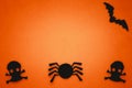 Halloween background with dark silhouette of a skull, spider, bat. Paper crafts. Orange backdrop, text space. Card, paper composit