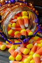 Halloween background frame consisting of a jar full of candy corn on a dark wooden table with a black table that you can personali Royalty Free Stock Photo