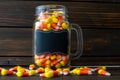 Halloween background frame consisting of a jar full of candy corn on a dark wooden table with a black table that you can personali Royalty Free Stock Photo