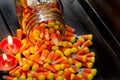 Halloween background frame consisting of a jar full of candy corn on a dark wooden table with a black table that you can personali Royalty Free Stock Photo