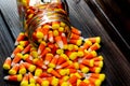 Halloween background frame consisting of a jar full of candy corn on a dark wooden table with a black table that you can personali Royalty Free Stock Photo