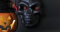 Halloween background. Glowing pumpkin and black skull on a dark background. Human fingers with long red claws