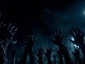 Halloween zombie hands reaching up from the ground in a foggy graveyard at night with dark blue and black tones