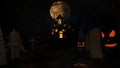 Halloween background with haunted house, ghost, bats and pumpkins, graves, at misty night spooky with fantastic big moon in sky. Royalty Free Stock Photo