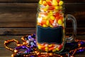 Halloween background of jar of candy corn and an assortment of voodoo bead on a dark wooden table. Royalty Free Stock Photo