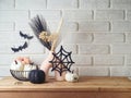 Halloween background with modern vase and decoration on wooden table over brick wall