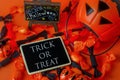 Halloween background - Trick or Treat on black wooden tag with pumpkin bag and black and orange candies on orange background Royalty Free Stock Photo