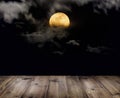 Wooden table over full moon with clouds at night. Royalty Free Stock Photo