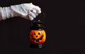 Halloween background. Zombie hand holding a lantern in the form of a pumpkin on a dark background. Halloween design. Copy space Royalty Free Stock Photo