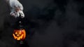 Halloween background. Zombie hand holding a lantern in the form of a pumpkin on a smoky dark background. Halloween design Royalty Free Stock Photo