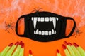 Halloween banner with wooden letters, spiders, witch fingers ,mask on orange background. Halloween during Corona virus