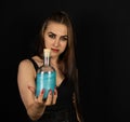 For Halloween, a beautiful witch brewed a potion. On a black background, a woman witch holds a bottle of poison in her Royalty Free Stock Photo