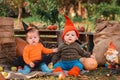 Halloween. Boy and girl in a holidays costume sitting in kitchen-garden. Children in costumes of witch and dwarf