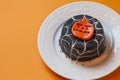 Halloween cake in a white plate. Surface orange background.