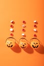 Halloween candies and three pumpkin shaped buckets against orange background