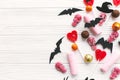 Halloween candy border with skulls, black bats, ghost, spider paper decorations on white wooden background, flat lay. Halloween Royalty Free Stock Photo