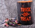 Halloween Candy piled next to Trick Or Treat bag on a spider web background