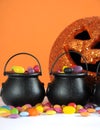 Halloween candy in trick or treat carry cauldrons with pumpkin - vertical closeup.