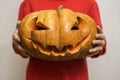 Halloween. Carved orange pumpkin on kid hands, jack-o-lantern traditional symbol of Halloween. Child is holding in his hands