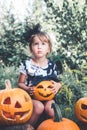 Halloween. Child dressed in black with jack-o-lantern in hand, trick or treat. Little girl pumpkin in the wood, outdoors.