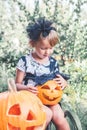 Halloween. Child dressed in black with jack-o-lantern in hand, trick or treat. Little girl pumpkin in the wood, outdoors.