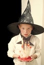 Halloween child in witch hat with bloody candle