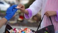 Halloween 2020: close-up of a gloved hand giving out candy to a young girl in a costume