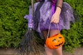 Halloween closeup witch purple skirt in and with broomstick and pumpkin.