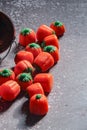 Halloween-colored pumpkin-shaped candy canes are placed on a gray table with sunlight in the background Royalty Free Stock Photo