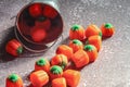 Halloween-colored pumpkin-shaped candy canes are placed on a gray table with sunlight in the background Royalty Free Stock Photo