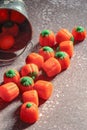 Halloween-colored pumpkin-shaped candy canes are placed on a gray table with sunlight in the background Royalty Free Stock Photo
