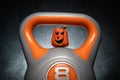 Halloween composition with ceramic Jack Lantern pumpkin on a gym kettlebell. Royalty Free Stock Photo