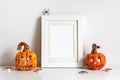 Halloween composition with ceramic pumpkins jack lantern and frame on table wall background. Greeting card template