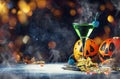 Halloween composition with festive drink, green cocktail and pumpkins lanterns, smoke and fallen leaves on night dark blue Royalty Free Stock Photo
