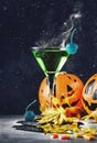 Halloween composition with green cocktail and pumpkins lanterns fire and smoke and fallen leaves on night dark background, vintage