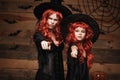 Halloween Concept - Beautiful caucasian mother and her daughter with long red hair in witch costumes with angry fussy facial expre