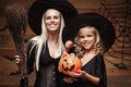 Halloween Concept - beautiful caucasian mother and her daughter in witch costumes celebrating Halloween with sharing Halloween can Royalty Free Stock Photo