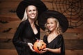 Halloween Concept - beautiful caucasian mother and her daughter in witch costumes celebrating Halloween with sharing Halloween can Royalty Free Stock Photo