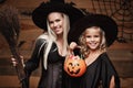 Halloween Concept - beautiful caucasian mother and her daughter in witch costumes celebrating Halloween with sharing Halloween can Royalty Free Stock Photo